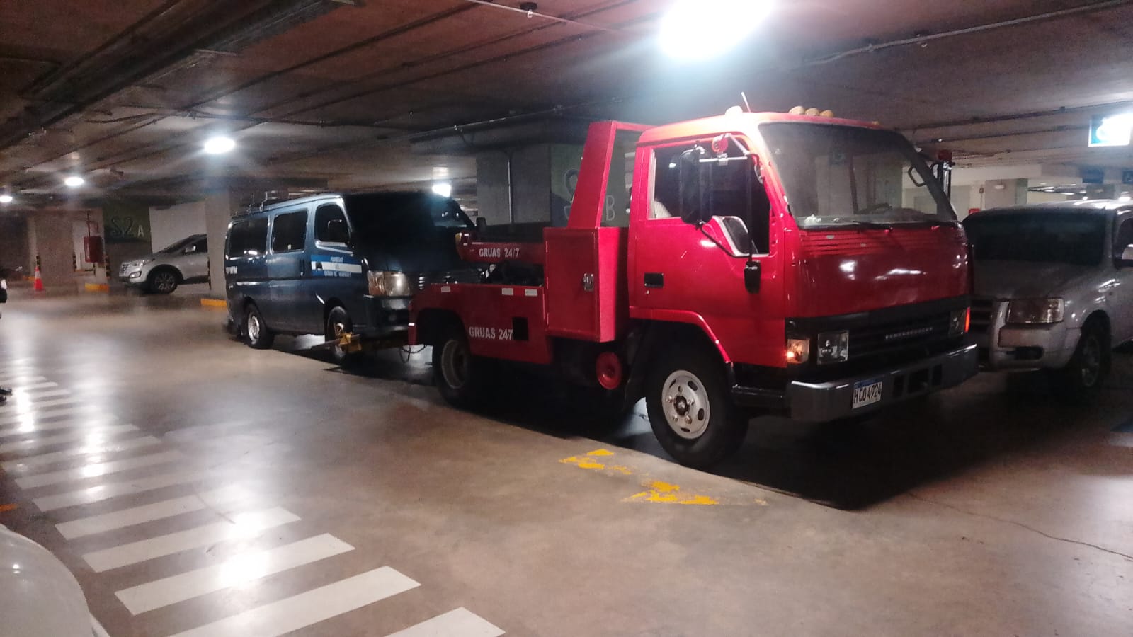 Grúa liviana de auxilio vial 24/7 remolcando una van